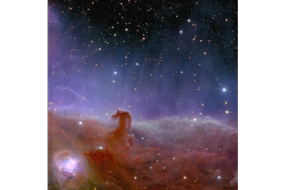 At the bottom of the screen, a large amount of reddish, hazy gas comes together to create a small hook shape to the left.  Above, a purple glow gradually fades toward the top of the image, showing a dark region of space with starry spots.