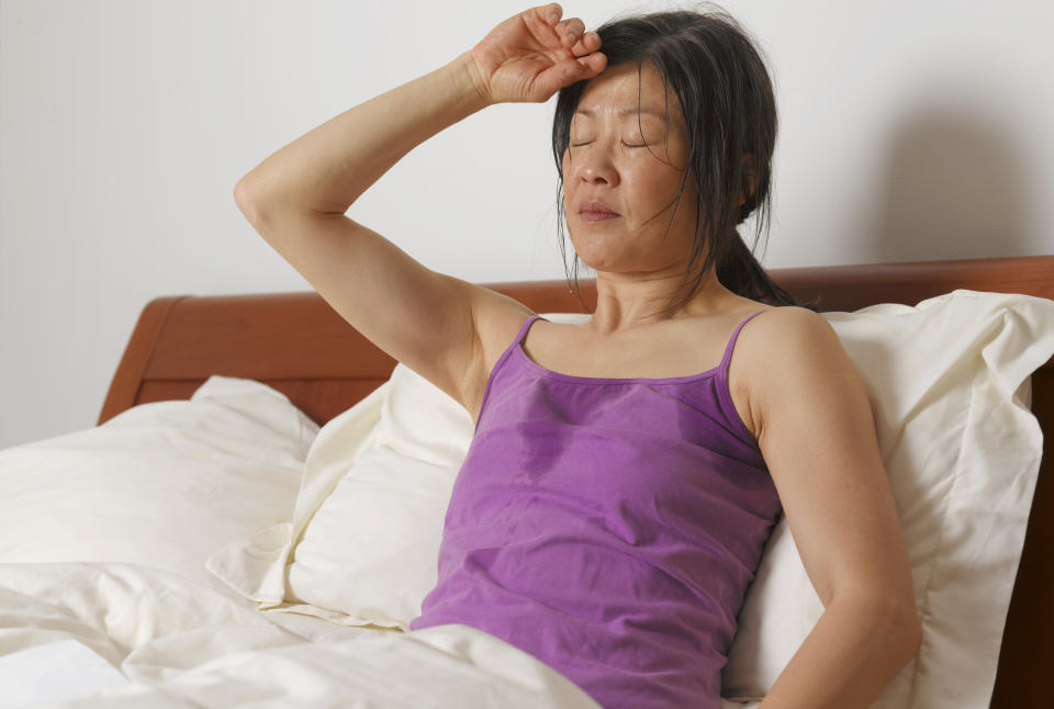 Middle-aged woman in menopause with hot flashes, lying in bed.  (Photo via Getty Images)