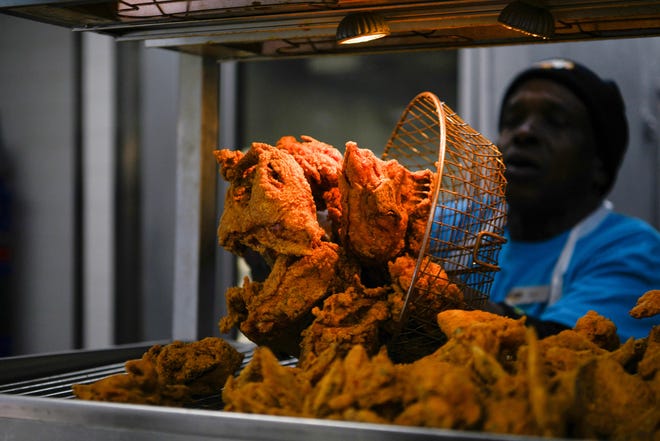A cook places freshly fried chicken on a platter as diners gather at Frenchy's Chicken, a Houston-based restaurant chain that received a mention in Beyoncé's hit film